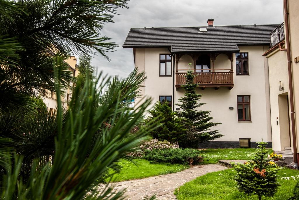 a white house with a balcony and a yard at Gimnazjalna 5 - Apartamenty i pokoje w Centrum Zakopanego in Zakopane