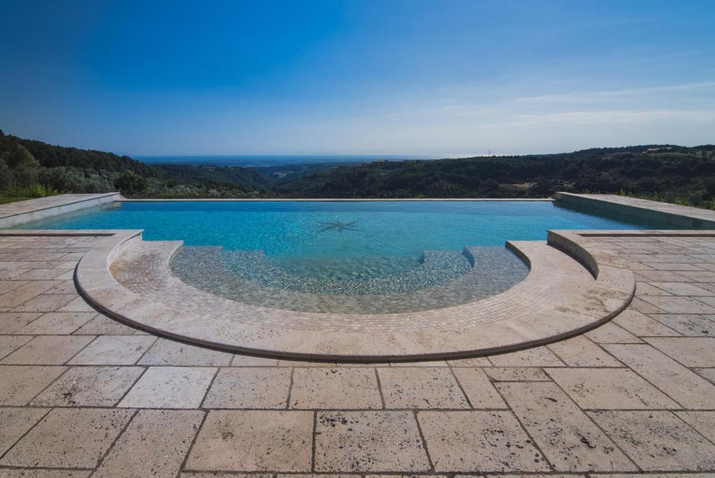 a pool with blue water in the middle of a patio at Villa Cava Alta in Riparbella