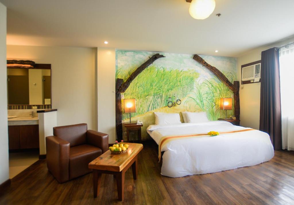 a hotel room with a bed and a chair at Nature's Village Resort in Bacolod