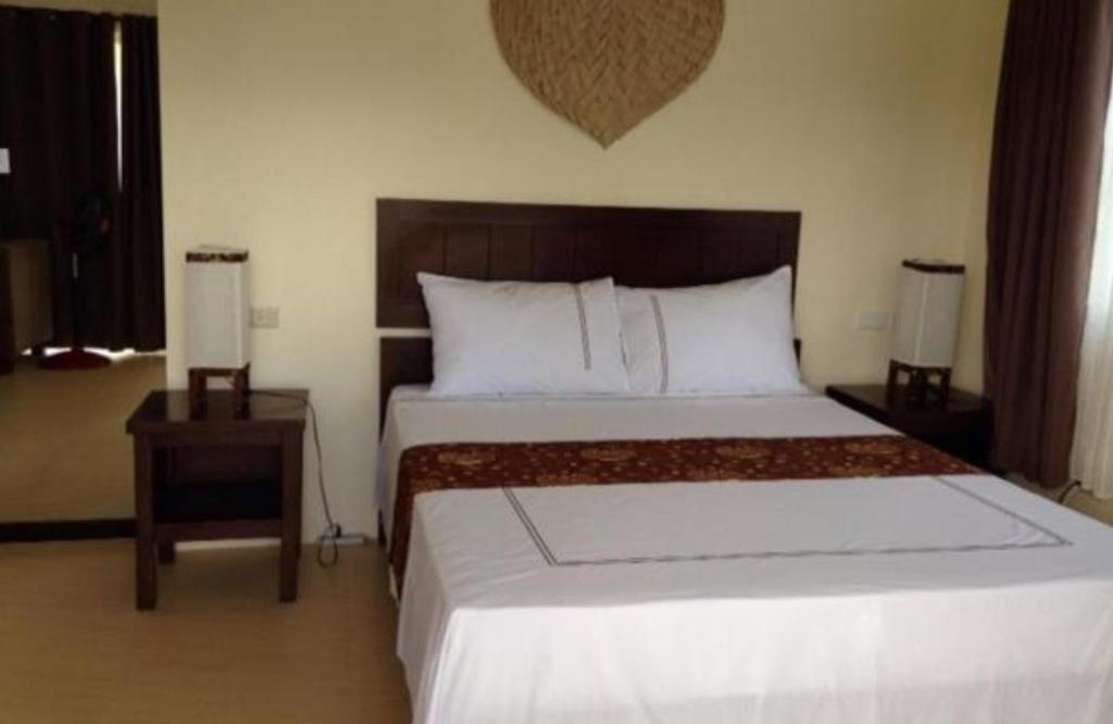a bedroom with a large bed with a wooden headboard at Kasagpan in Tagbilaran City