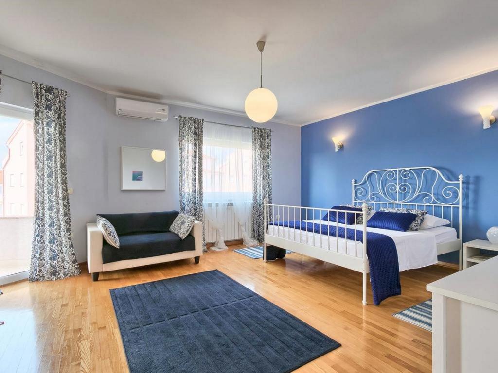 een blauwe slaapkamer met een bed en een stoel bij Villa Carmen in Štinjan