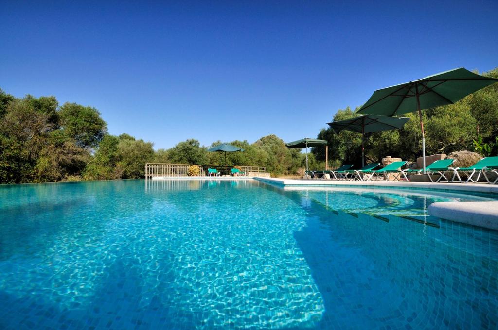 ein großer Pool mit blauem Wasser, Stühlen und Sonnenschirmen in der Unterkunft Agroturismo Sa Vall in Son Macia