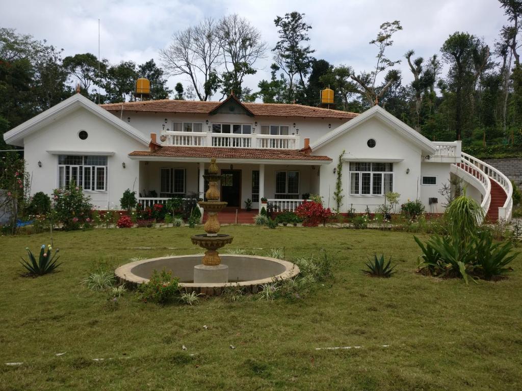 uma casa branca com uma fonte no quintal em Robin Woods Homestay em Sakleshpur