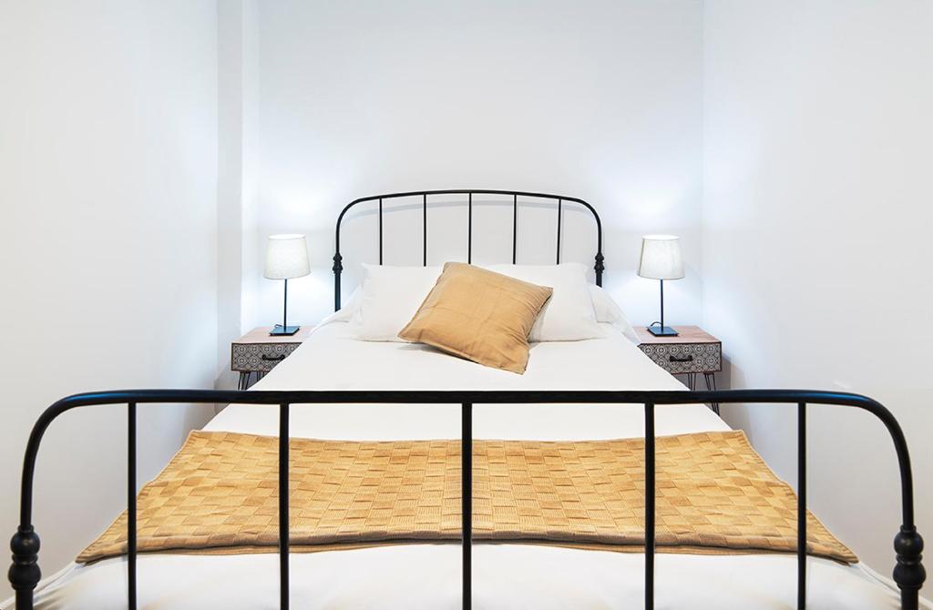 セビリアにあるEl Hogar de Dueñasの黒金属製のベッドフレームとランプ2つ付きのベッド