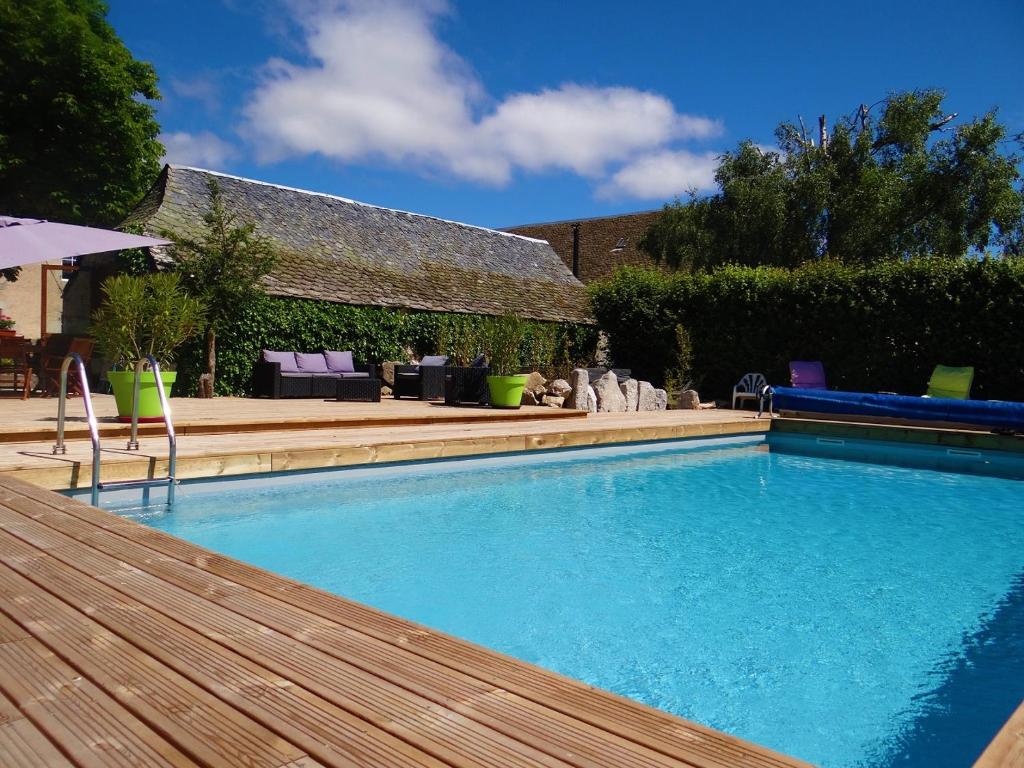 a large swimming pool with a wooden deck next to a house at La maison de Gilbert in Chaudes-Aigues