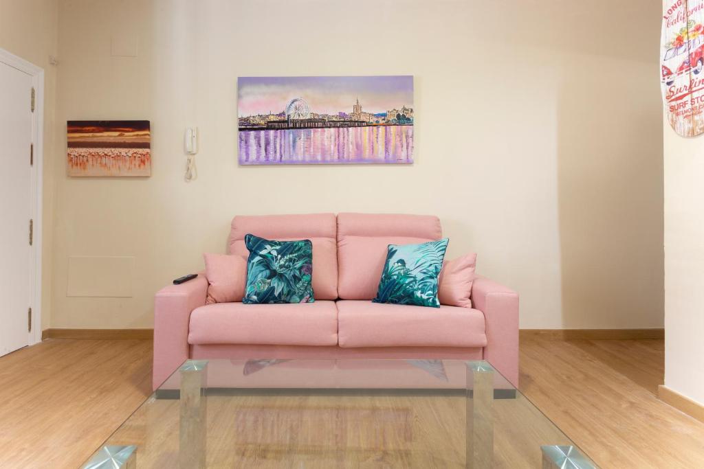 Sofá rosa en la sala de estar con mesa de cristal en Flamingo Apartment, en Málaga