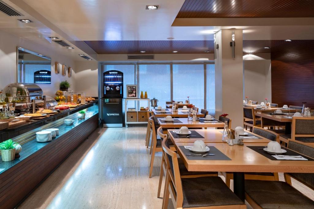 a restaurant with wooden tables and chairs and a kitchen at Vincci Puertochico in Santander
