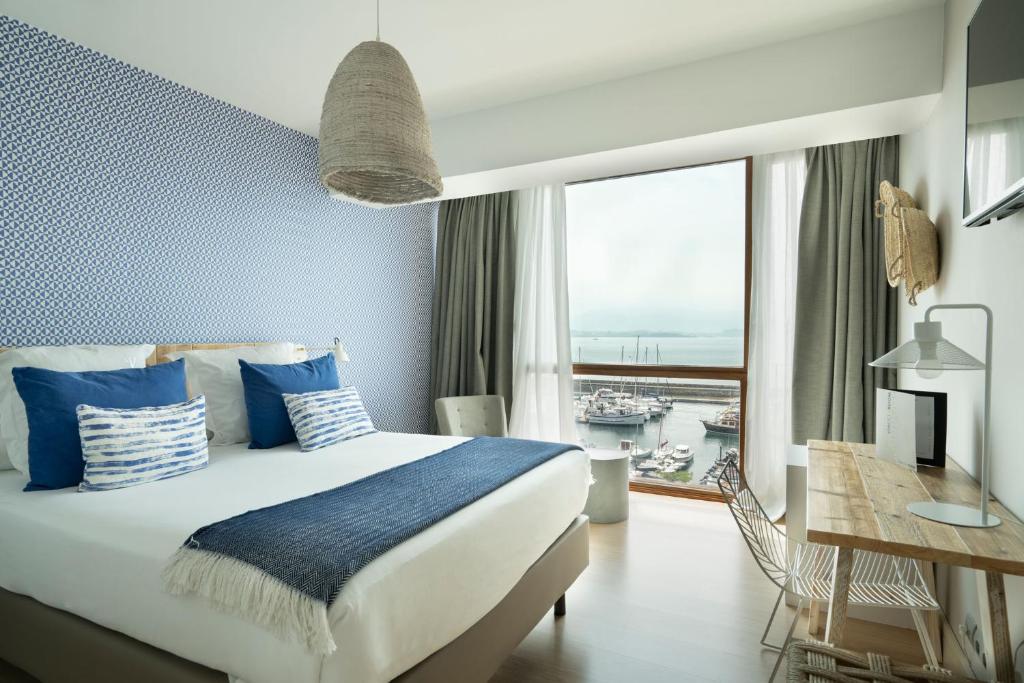 a bedroom with a large bed and a large window at Vincci Puertochico in Santander