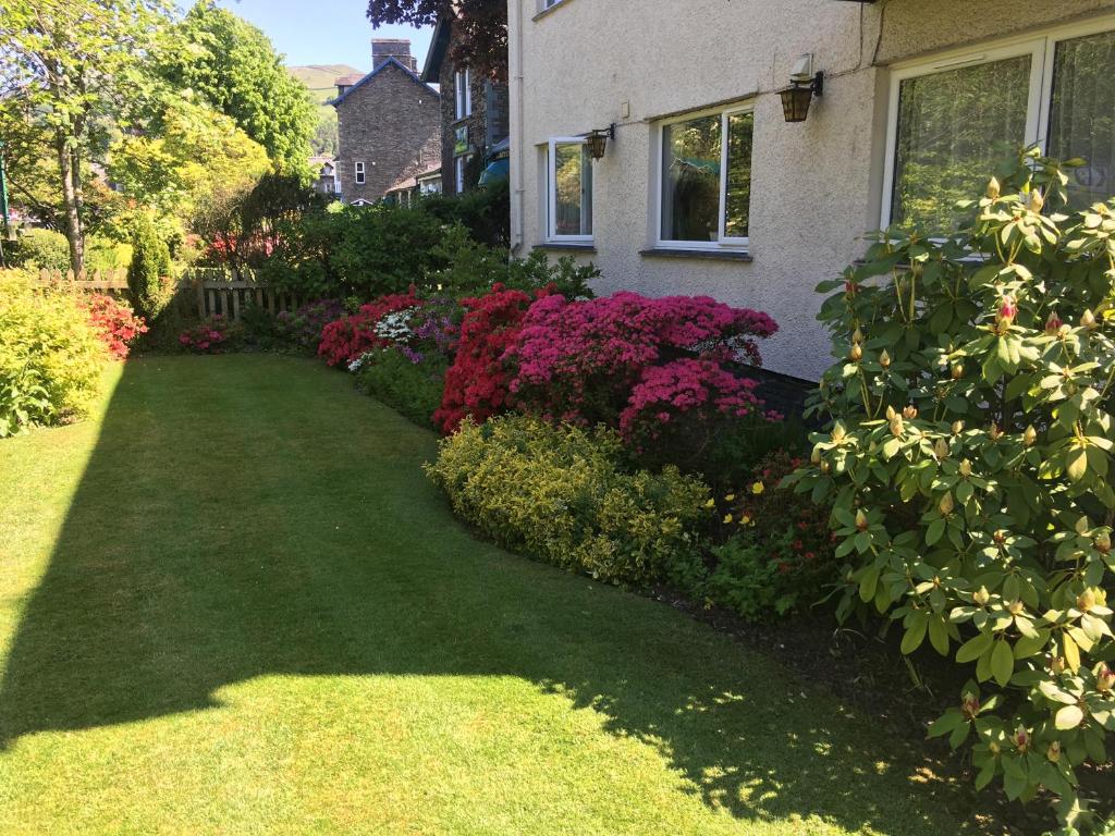 una casa con un giardino di fiori in un cortile di Rothay House ad Ambleside