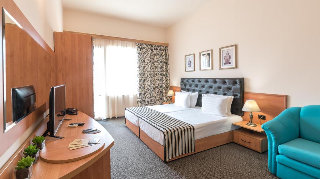 a hotel room with a bed and a desk at Lotus Family Hotel - Free Parking in Sunny Beach