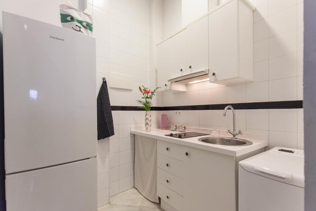 Biała kuchnia ze zlewem i lodówką w obiekcie Precioso Apartamento Sevilla Centro w Sewilli