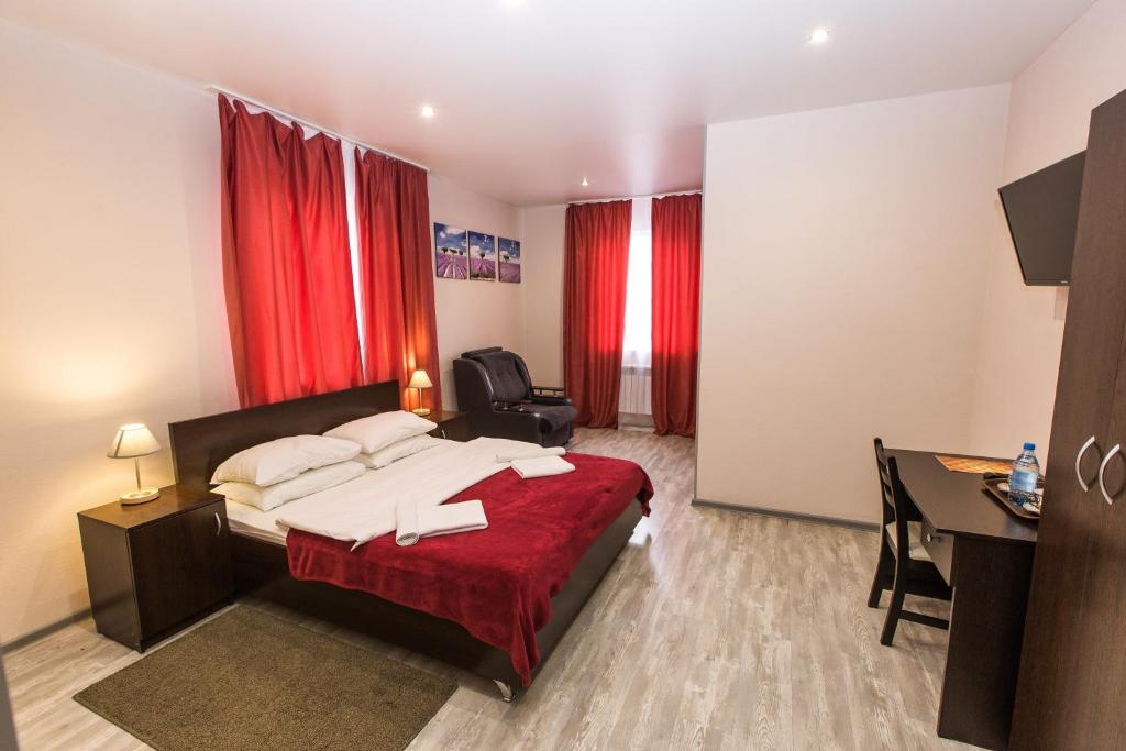 1 dormitorio con cama, escritorio y cortinas rojas en Asti Rooms Hotel, en Tomsk