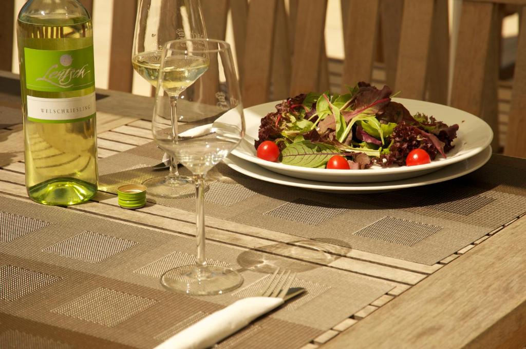 a table with a plate of salad and a bottle of wine at Storchencamp Gästehaus Purbach in Purbach am Neusiedlersee