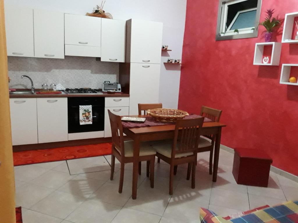 カステッランマーレ・デル・ゴルフォにあるCasa di Loryの赤い壁のキッチン(テーブル、椅子付)