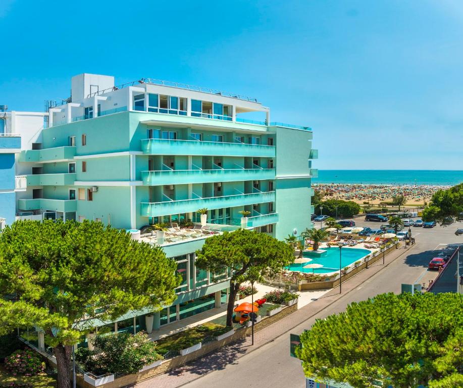 an apartment building with a pool and a beach at Hotel Montecarlo in Bibione