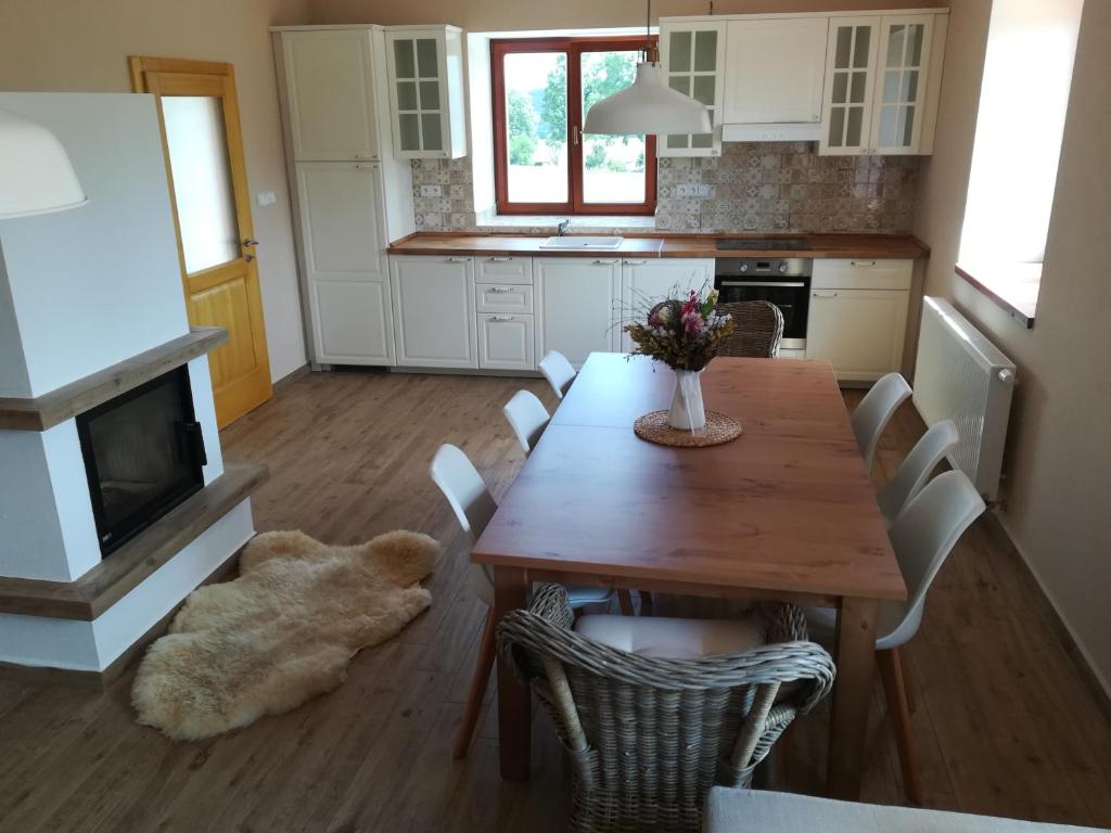 a kitchen with a wooden table with chairs and a dog on the floor at Chalupa u lesa - Nova Ves in Český Rudolec