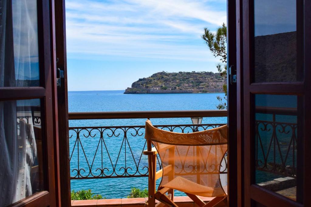 a chair sitting on a balcony looking out at the ocean at The Island sea view apartment in Elounda