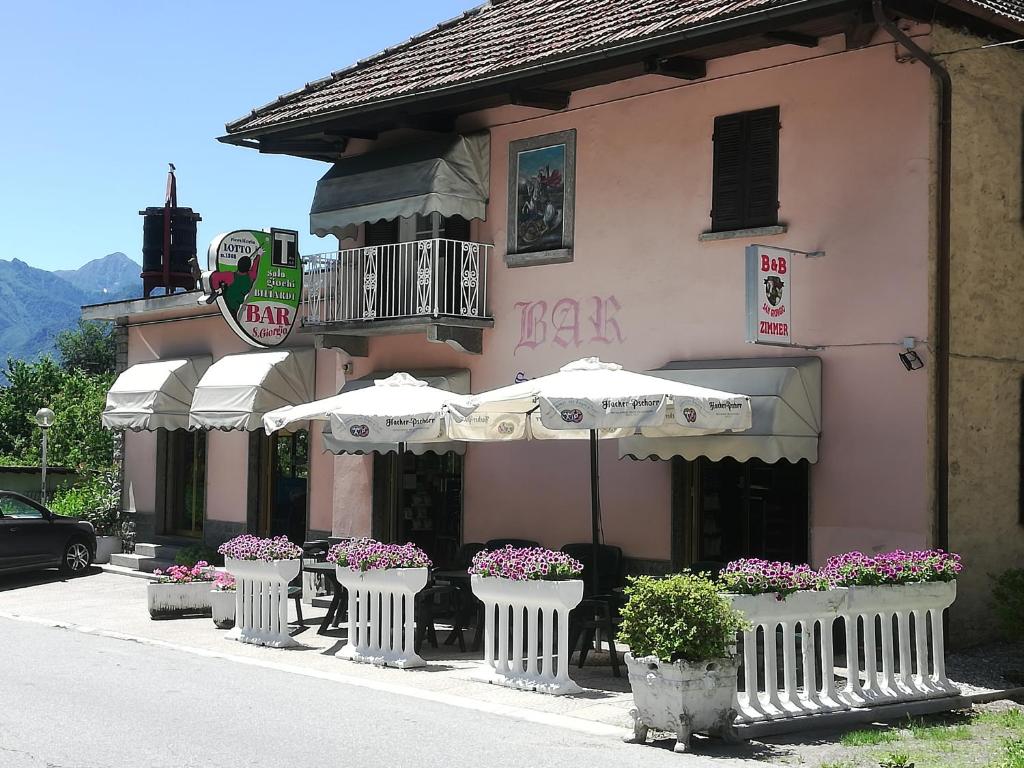 un edificio rosa con ombrelli bianchi e fiori in vasi di B&B SAN GIORGIO a Domodossola