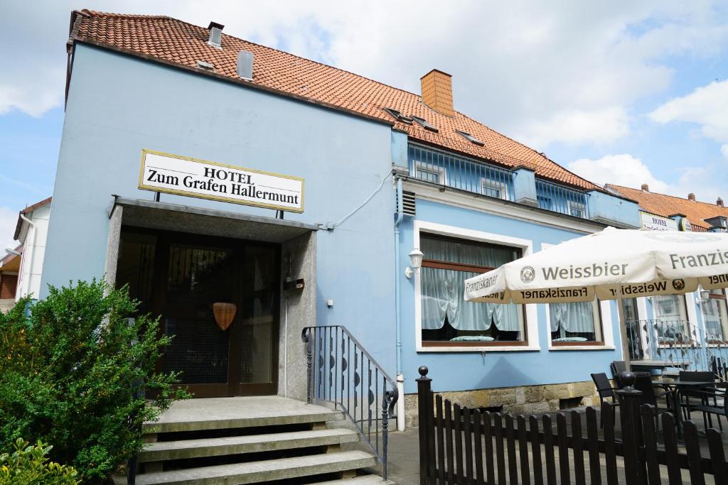 a blue building with a staircase leading to the door at Hotel zum Grafen Hallermunt in Springe