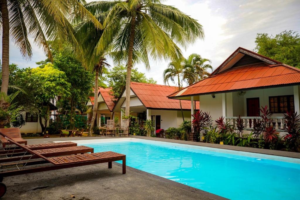 a swimming pool in front of a house with palm trees at Fullmoon House Samui in Lamai