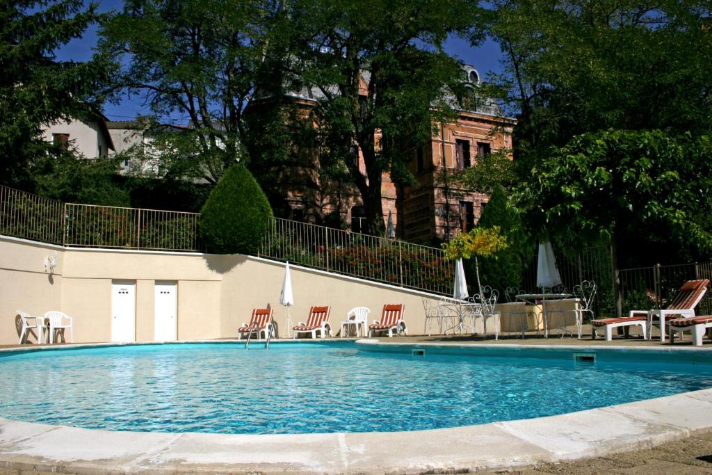 una grande piscina con sedie e un edificio di Relais Saint Roch a Saint-Alban-sur-Limagnole