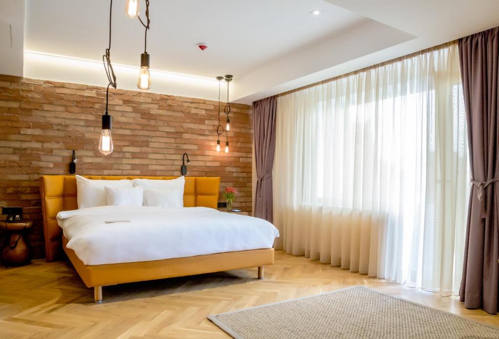 a bedroom with a large bed and a brick wall at Caro Hotel in Bucharest
