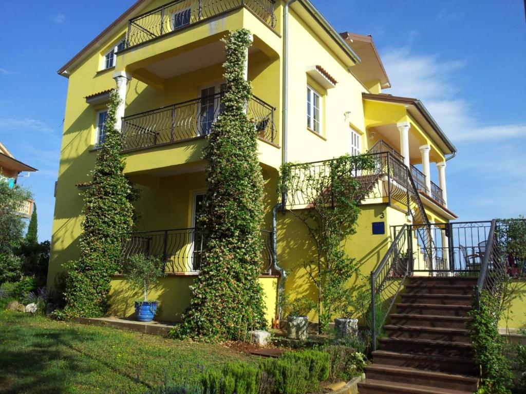 Una casa amarilla con hiedra a un lado. en Apartment Luiza Funtana, en Funtana