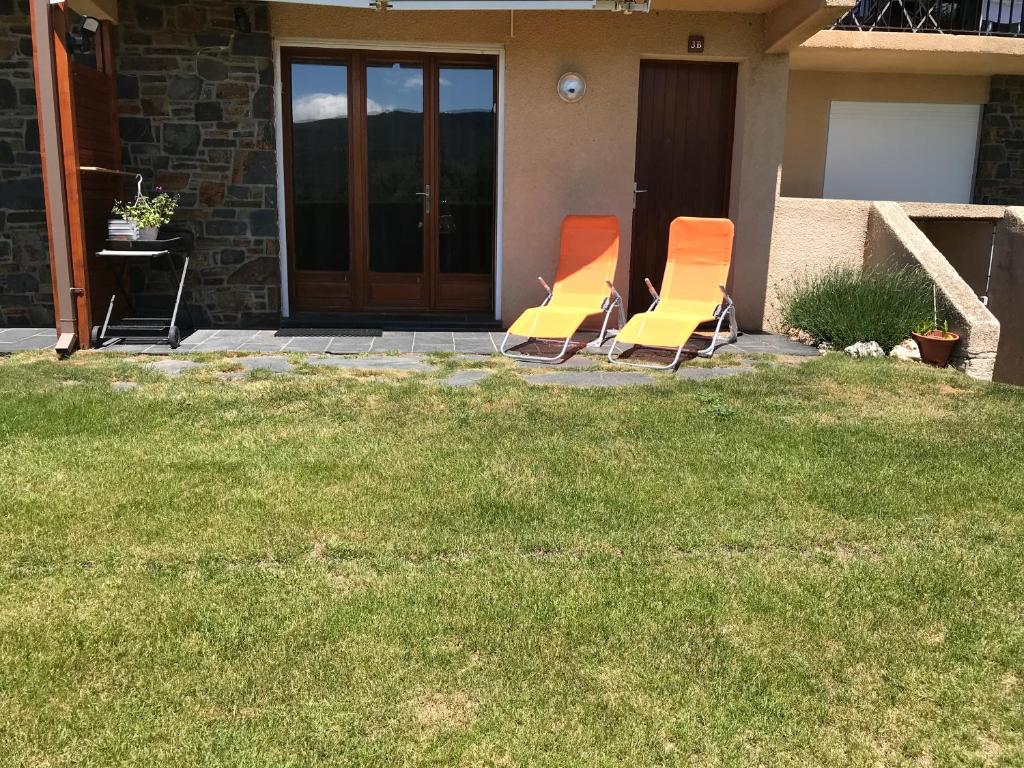dos sillas naranjas sentadas frente a una casa en Appartement A La Montagne, en Palau-de-Cerdagne