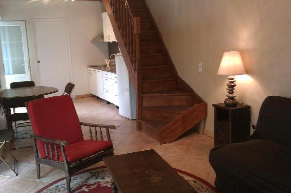 a living room with a red chair and a table at La petite maison pour 5 personnes in Évran