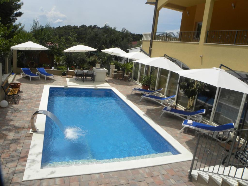 a swimming pool with chairs and umbrellas next to a building at Anka Strman in Makarska