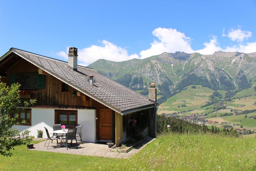 a house with a table and chairs and mountains at Les Mourriaux in Chateau-d'Oex