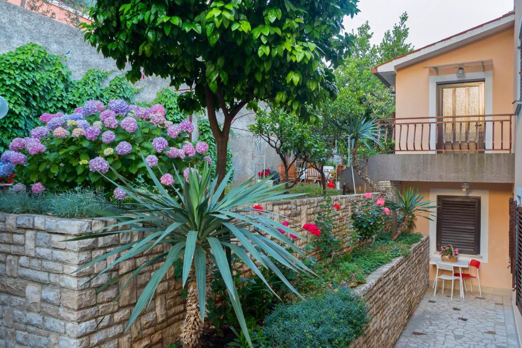 een tuin voor een huis met bloemen bij Apartments Emilia in Rabac