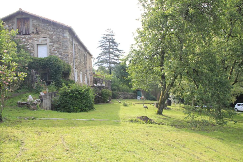 une vieille maison en pierre dans une cour herbeuse avec un arbre dans l'établissement Gîte Valescure, à Saint-Michel-de-Dèze