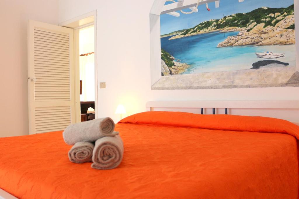 サンタ・テレーザ・ガッルーラにあるResidence Ponenteのベッドルーム1室(オレンジ色のベッド1台、タオル付)