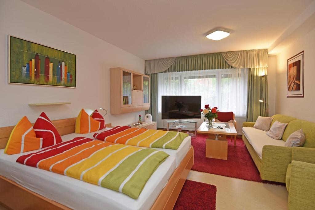 a bedroom with a large bed and a living room at Hotel Haus Orchideental Jena in Jena