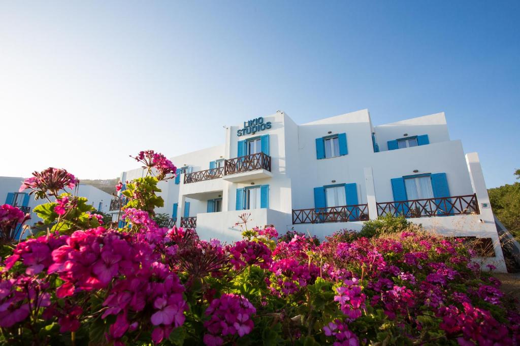 a white building with blue windows and pink flowers at Likio Studios in Batsi