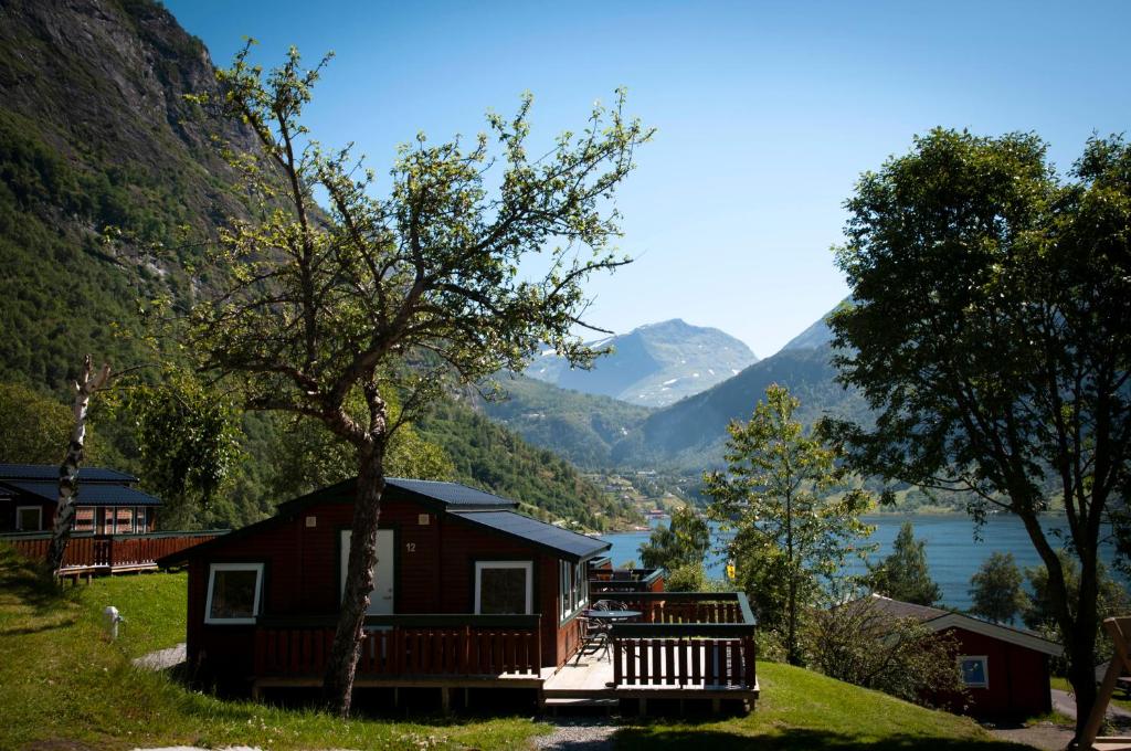 a cabin with a view of a lake and mountains at Grande Hytteutleige og Camping in Geiranger