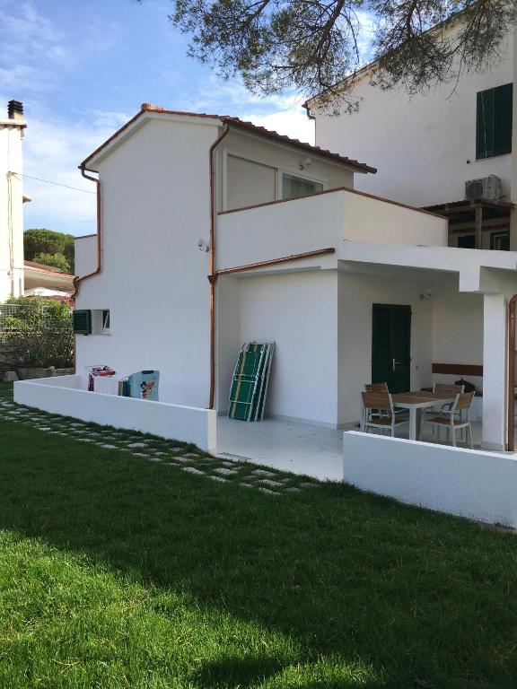 a white house with a table in the backyard at villetta sul mare Rachele in Marina di Campo