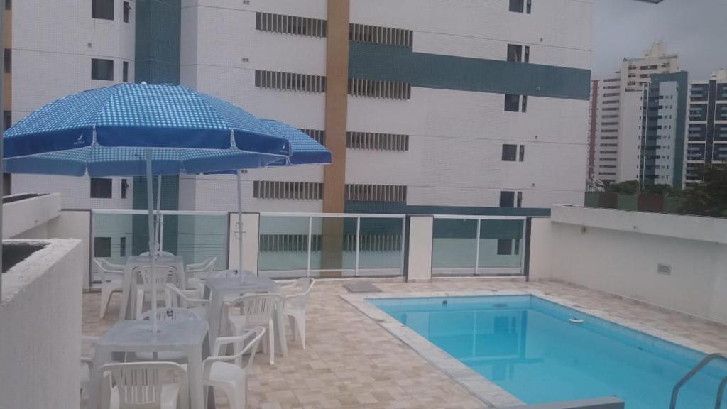 uma piscina com mesas e cadeiras e um guarda-sol em Pousada Beira Mar em Recife