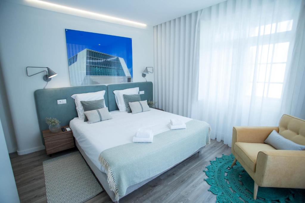 a bedroom with a large bed and a chair at Boavista Premium Family & Business by Porto City Hosts in Porto