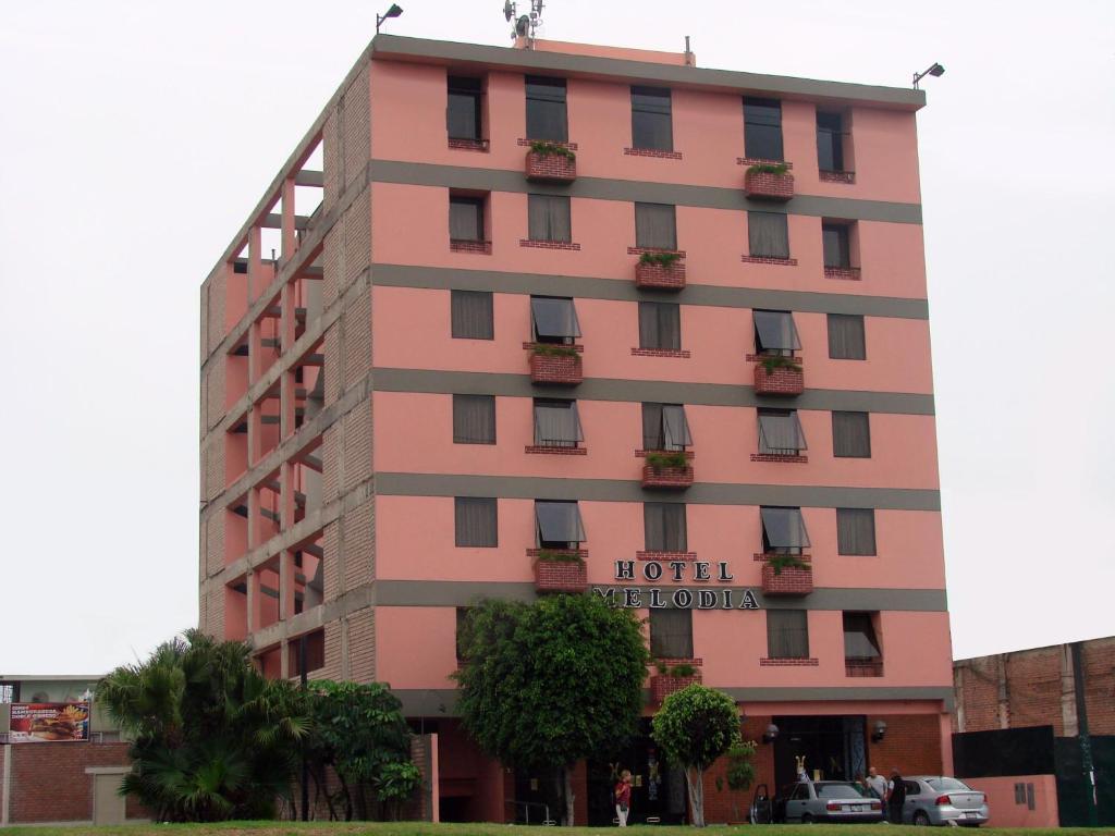 un edificio de hotel rosa con un cartel en él en Hotel Melodia en Lima
