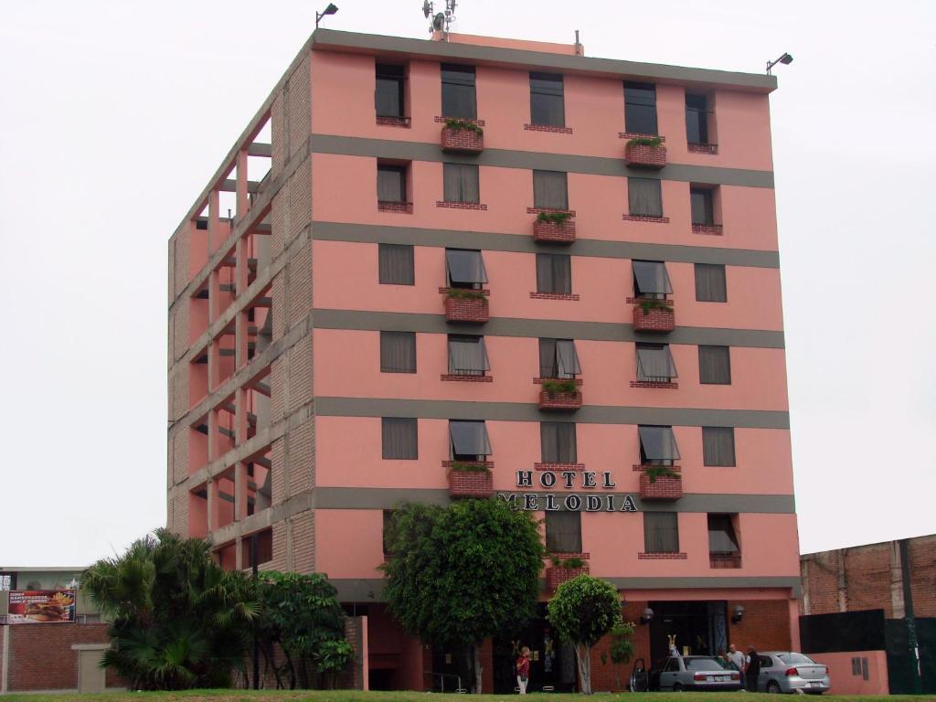 a pink hotel building with a sign on it at Hotel Melodia in Lima