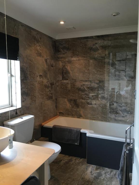 a bathroom with a tub and a toilet and a sink at Craster Crew House in Craster
