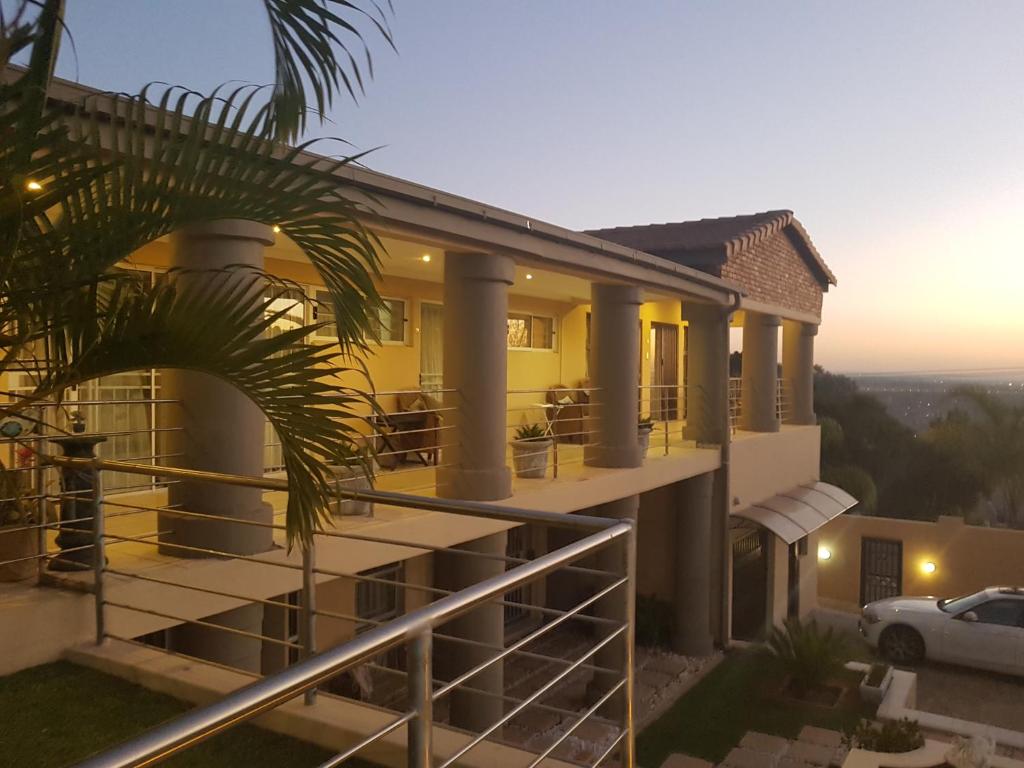 een huis met een balkon met een palmboom bij Aquila Guest House in Pretoria