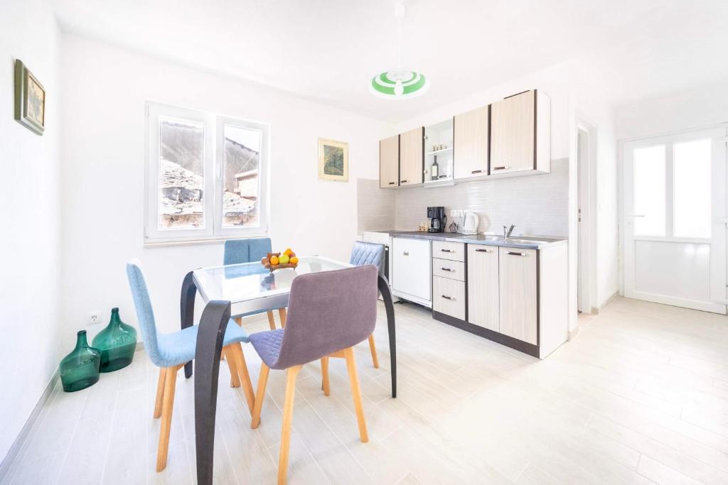 eine Küche mit einem Tisch und Stühlen im Zimmer in der Unterkunft Apartmani Ada 1 in Povlja