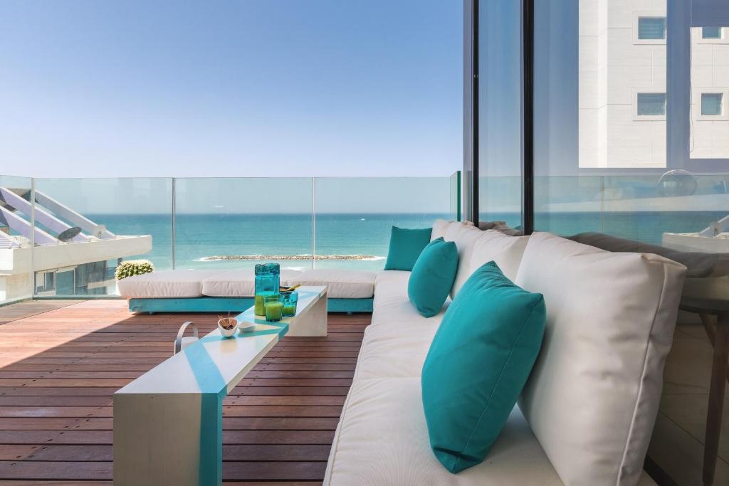 a living room with a white couch and blue pillows at Hayarkon 29 - Next Royal Beach in Tel Aviv