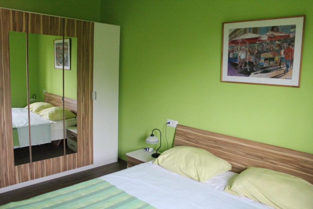 a green bedroom with a bed and a mirror at Primavera in Omišalj