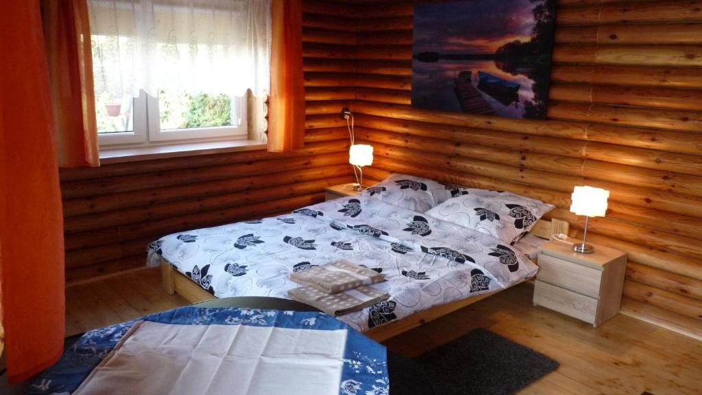 ムロンゴヴォにあるDomek w ogrodzieのログキャビン内のベッドルーム1室(ベッド2台付)