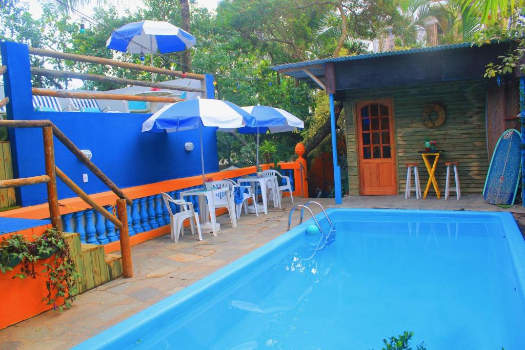 a swimming pool next to a house with an umbrella at Canto das Laranjeiras Tombo in Guarujá