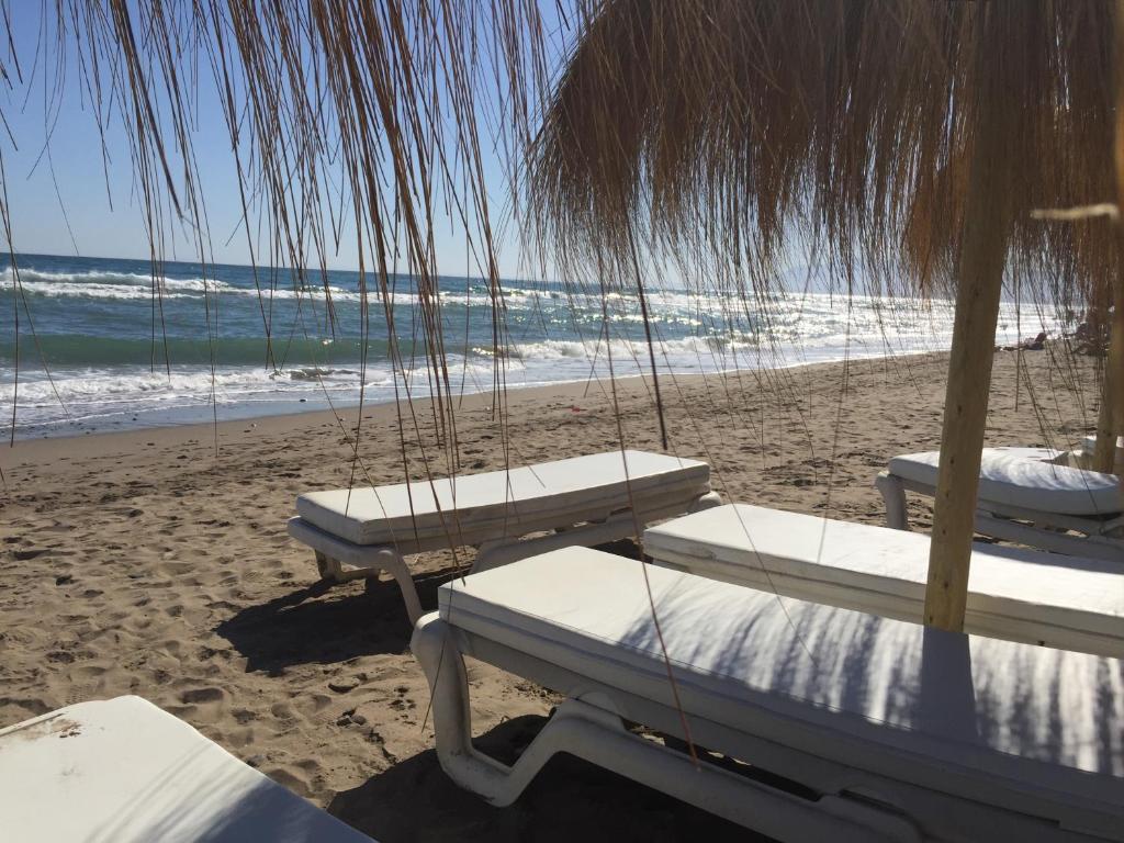 dois bancos balançando em uma praia com o oceano em Casa Piscina em Marbella